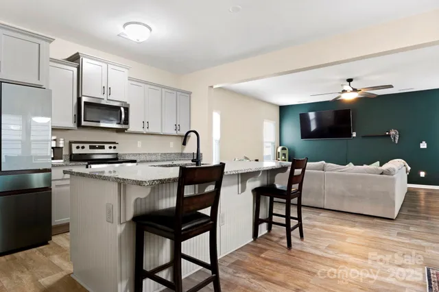 a living room with furniture a flat screen tv and kitchen view