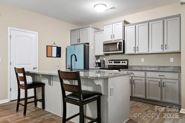 a kitchen with stainless steel appliances granite countertop a stove a refrigerator a microwave and white cabinets