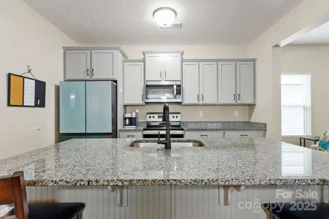 a kitchen with stainless steel appliances granite countertop a sink refrigerator and cabinets