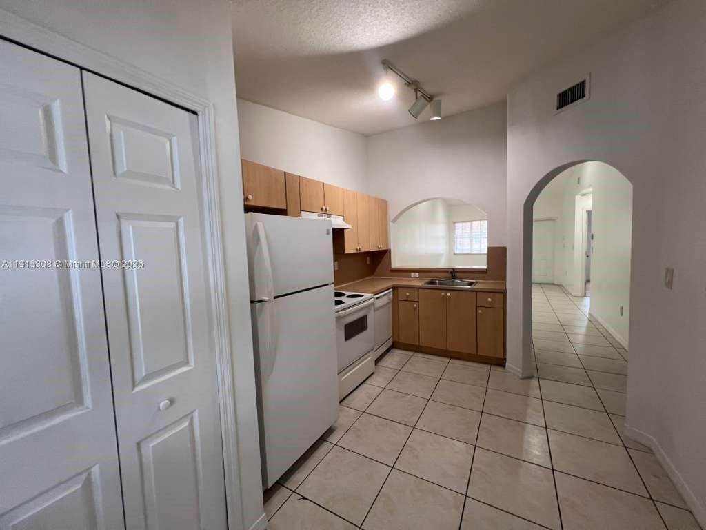 a kitchen with granite countertop a refrigerator and a sink