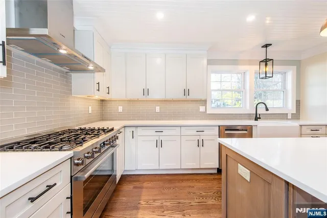 a kitchen with stainless steel appliances granite countertop a sink a stove a refrigerator and island with wooden floor