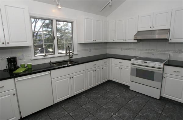 a white kitchen with granite countertop white cabinets and white stainless steel appliances