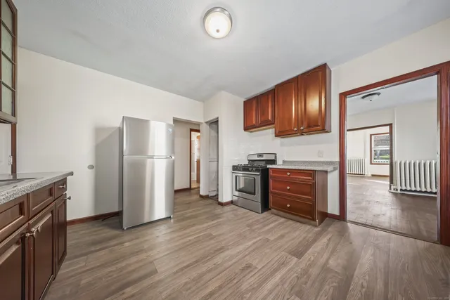a kitchen with stainless steel appliances granite countertop a refrigerator cabinets and wooden floor