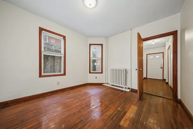 a view of an empty room with window and wooden floor