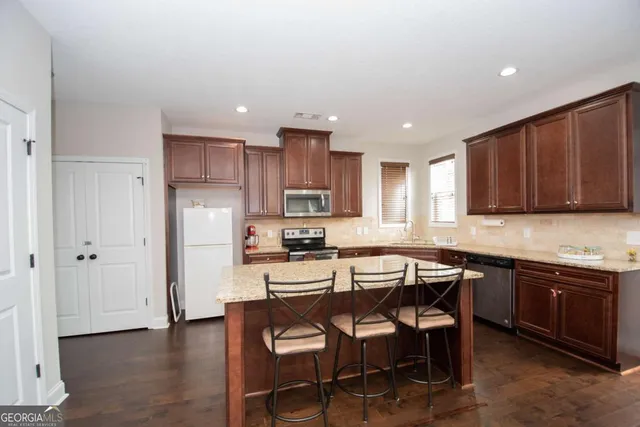 a kitchen with stainless steel appliances granite countertop a table chairs sink refrigerator and cabinets