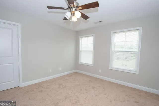 an empty room with windows and fan