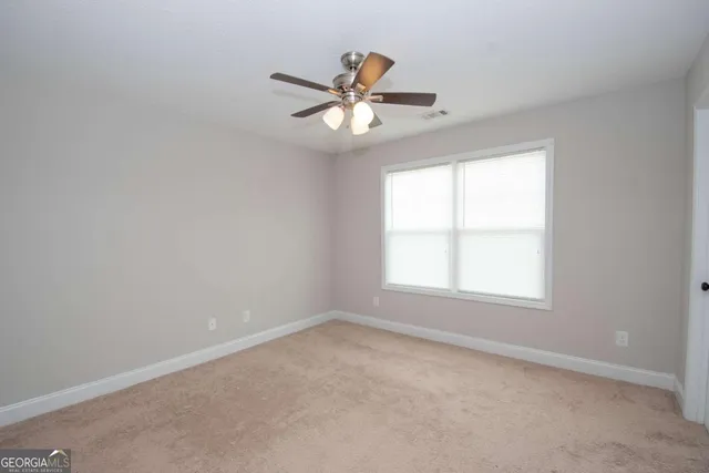 an empty room with a window and a fan