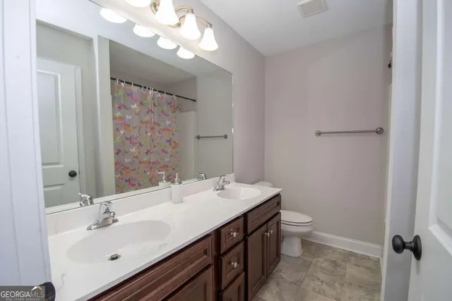 a bathroom with a double vanity sink mirror and toilet