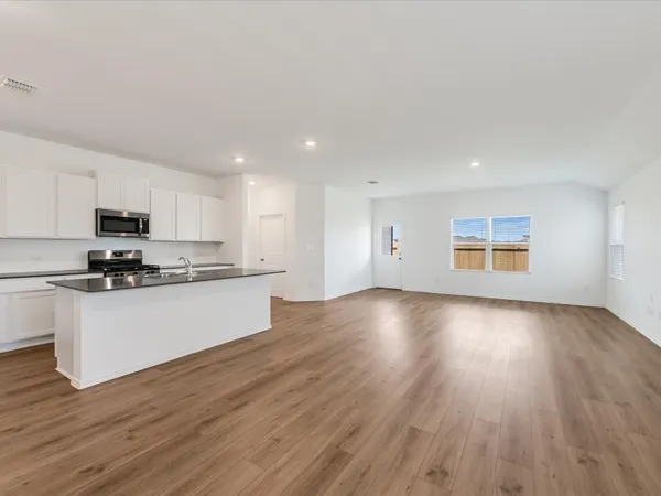 a view of kitchen with granite countertop wooden floors stainless steel appliances and sink