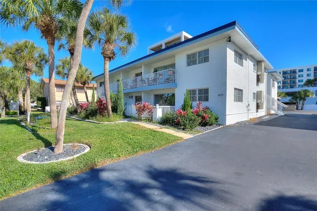 a front view of a house with garden and trees