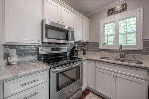 a kitchen with granite countertop a stove a sink and a microwave