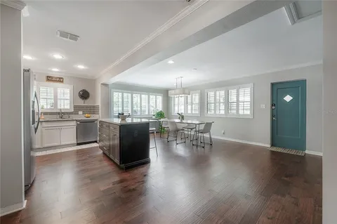 a view of kitchen and dining room with furniture a potted plant and wooden floor