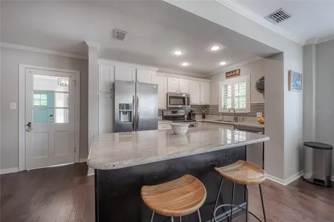 a kitchen with stainless steel appliances granite countertop a kitchen island and chairs in it