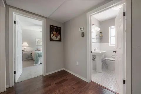 a view of a hallway with wooden floor and a bathroom
