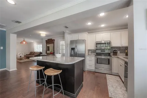 a kitchen with stainless steel appliances kitchen island granite countertop a table chairs stove and refrigerator