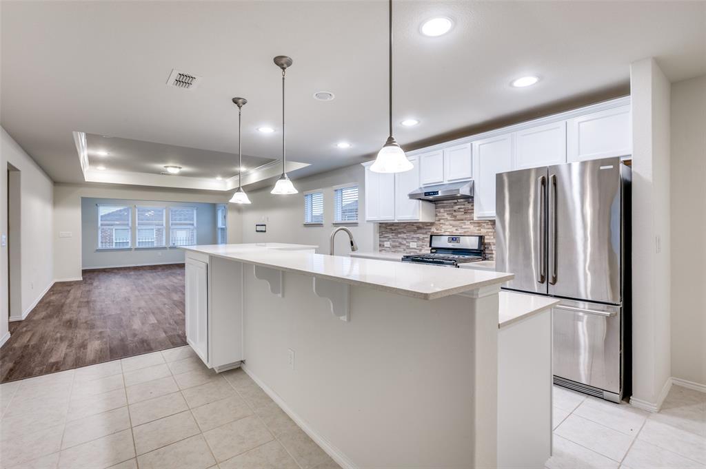 7793 Gulf Walk Road Frisco, TX 75036 - Photo 3 of 28 a kitchen with kitchen island a refrigerator a sink and a oven