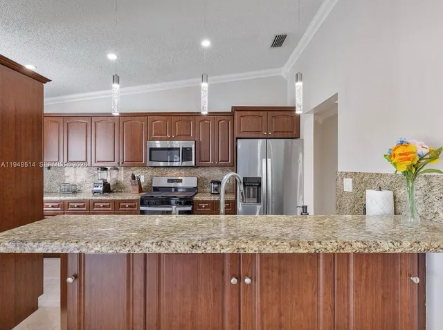 a kitchen with stainless steel appliances granite countertop a kitchen island hardwood floor sink and stove