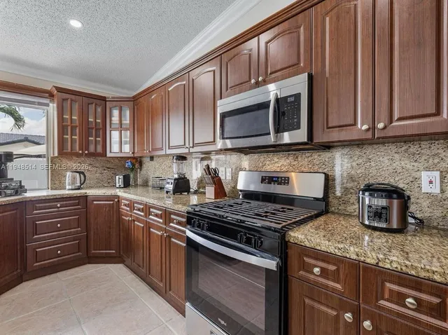 a kitchen with granite countertop a stove top oven a sink dishwasher and cabinets