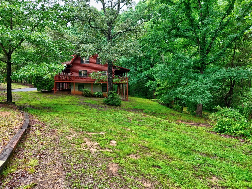 237 Spring Valley Road Liberty, SC 29657 - Photo 36 of 50 A charming log cabin with a spacious deck nestles into a verdant hillside, surrounded by mature trees.