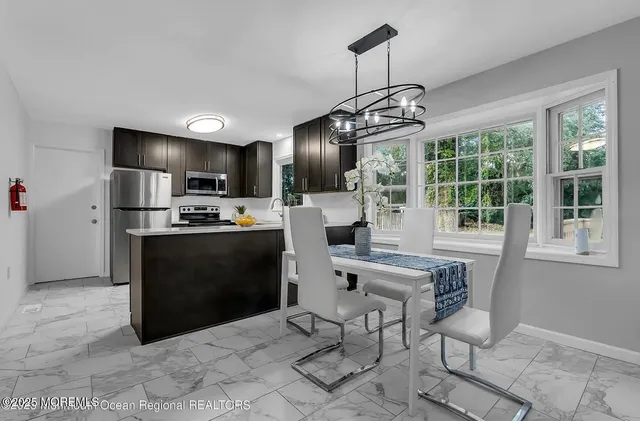 a kitchen with granite countertop a refrigerator a stove top oven a sink dishwasher a dining table and chairs with wooden floor