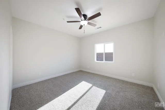 an empty room with ceiling fan and window