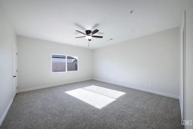 an empty room with a chandelier fan and windows