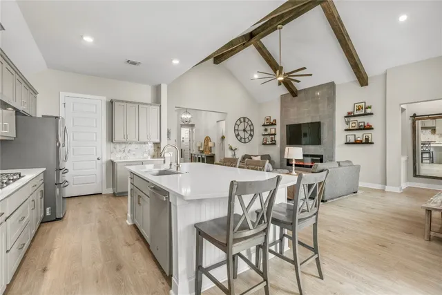 a kitchen with stainless steel appliances kitchen island granite countertop a table chairs refrigerator and microwave