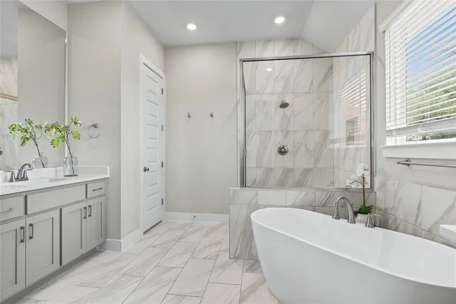 a bathroom with a bathtub a sink a window and a shower