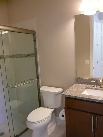 a bathroom with a granite countertop sink toilet mirror and bathtub