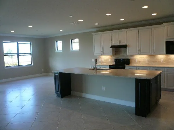 a kitchen with kitchen island granite countertop a sink a stove and a refrigerator