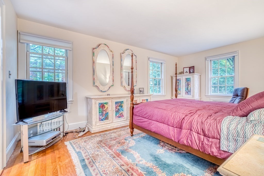 222 Bonad Road Brookline, MA 02467 - Photo 14 of 30 a bedroom with a bed a flat screen tv and a large window with the garden view
