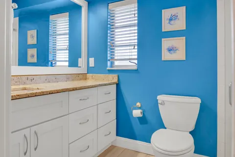 a bathroom with a granite countertop toilet sink and mirror