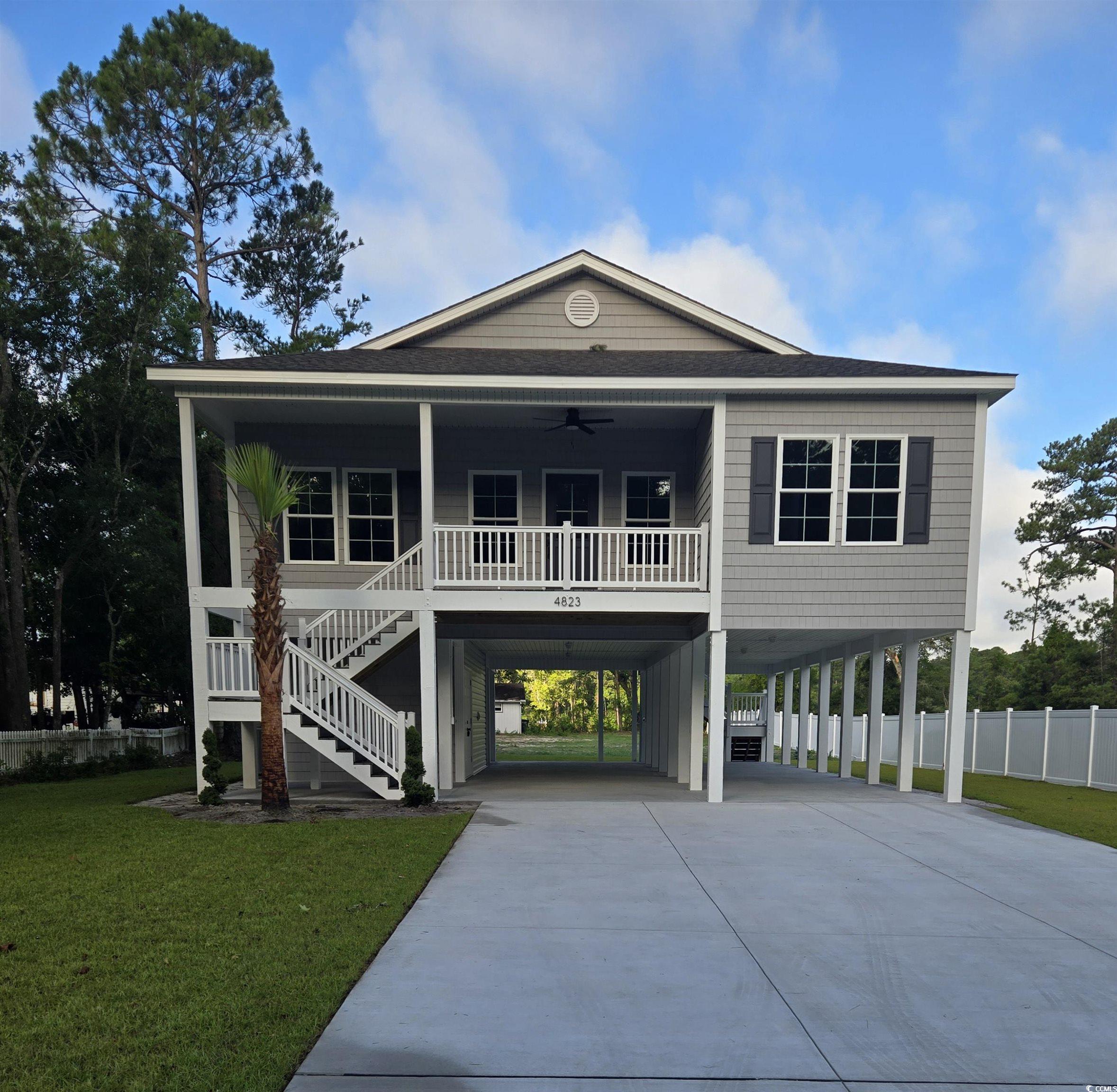 Coastal inspired home featuring a carport, a ceili