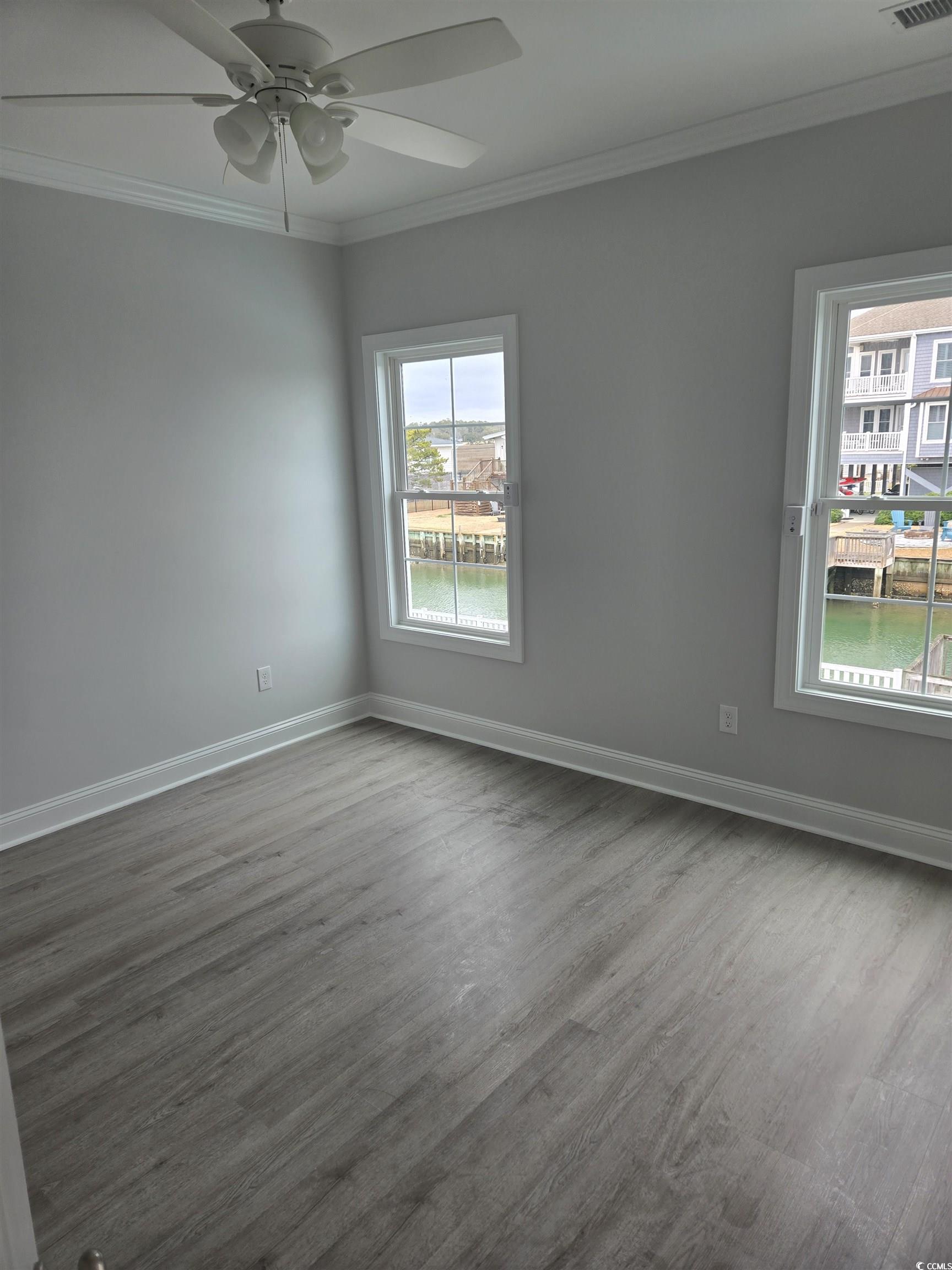 Empty room featuring crown molding, dark wood-styl