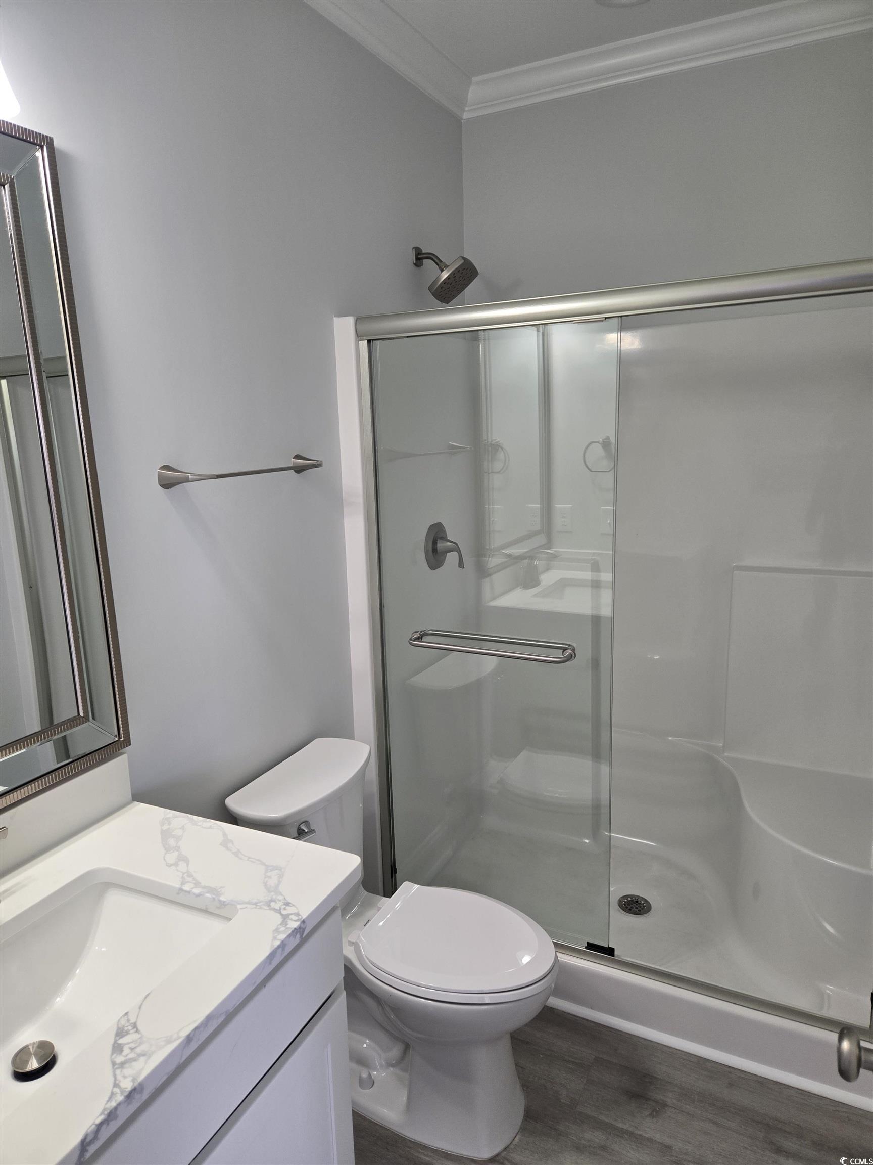 Full bathroom featuring toilet, wood finished floo