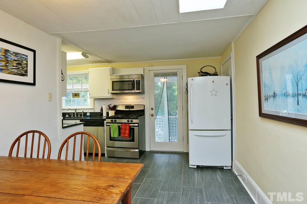 526 North Person Street Raleigh, NC 27604 - Photo 11 of 25 a kitchen with stainless steel appliances granite countertop a refrigerator a stove a sink a dining table and chairs with wooden floor