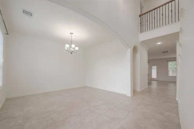 an empty room with chandelier fan and windows