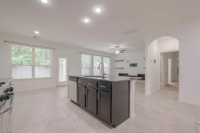 a large kitchen with kitchen island granite countertop a stove a sink a refrigerator and white cabinets with wooden floor