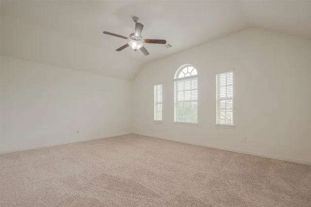 an empty room with windows and chandelier fan