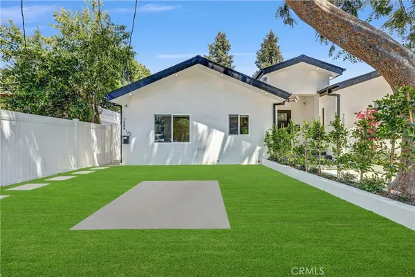 a view of a yard in front of a house with plants and a patio