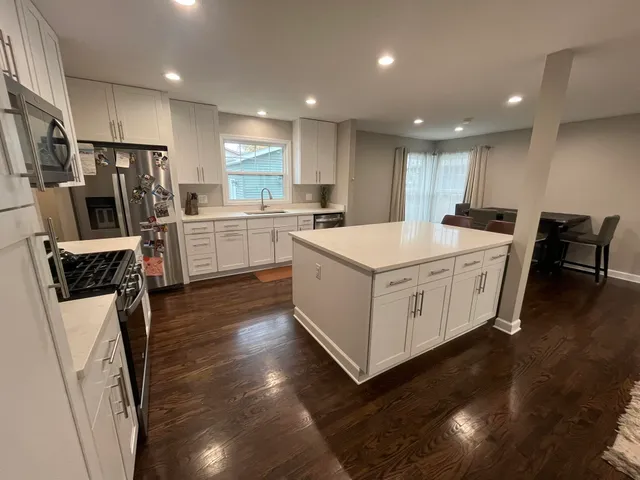 a large white kitchen with wooden floors and stainless steel appliances