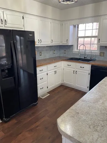 a kitchen with stainless steel appliances granite countertop a refrigerator a sink a stove and white cabinets