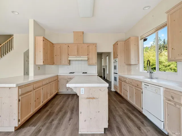 a view of an empty room with wooden floor and fan