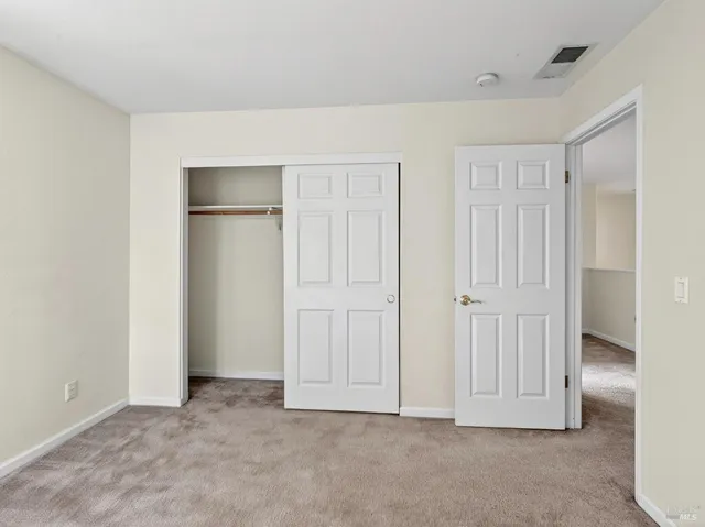 a spacious bedroom with a large bed a couch and paintings on the wall