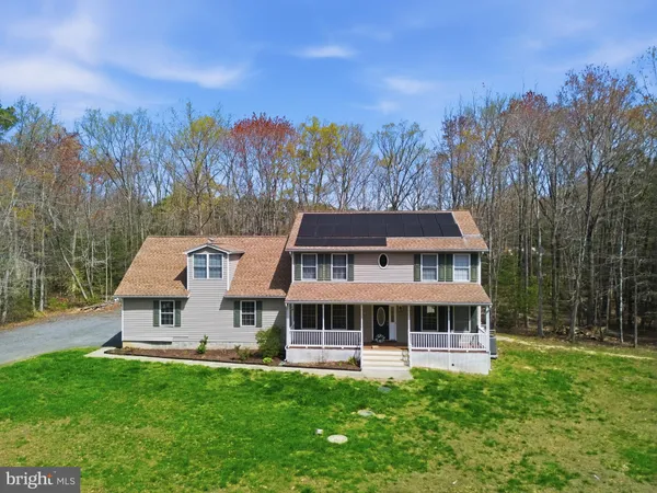 a front view of a house with a big yard and large trees