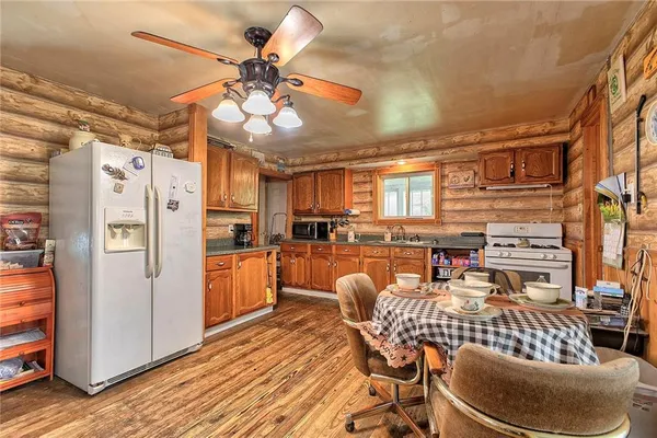 a kitchen with stainless steel appliances granite countertop a refrigerator a stove and white cabinets with wooden floor