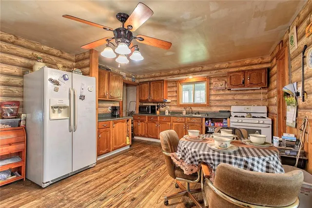 a kitchen with stainless steel appliances granite countertop a refrigerator a stove and white cabinets with wooden floor