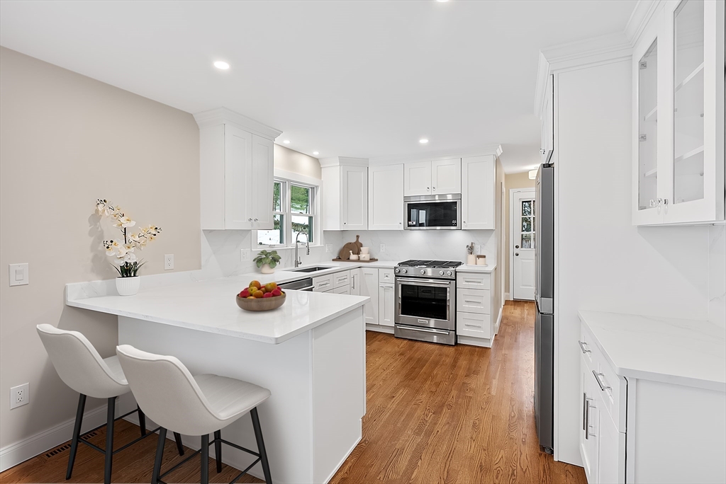 34 Pleasant Street, Unit 5 Wellesley, MA 02482 - Photo 2 of 31 a kitchen with stainless steel appliances a stove top oven a refrigerator a sink and white cabinets with wooden floor