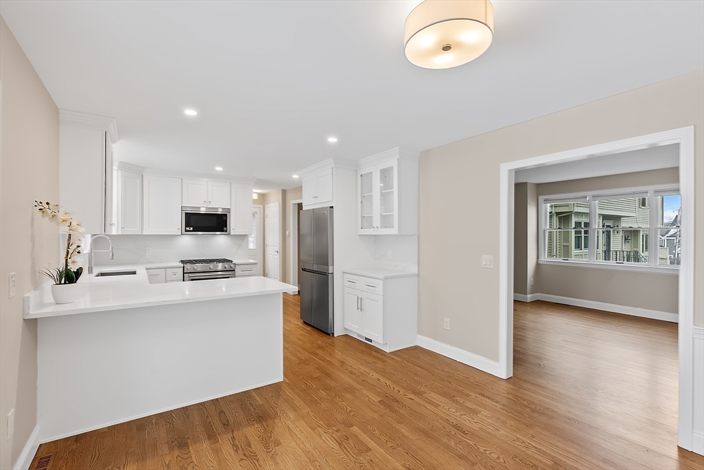 34 Pleasant Street, Unit 5 Wellesley, MA 02482 - Photo 4 of 31 a kitchen with stainless steel appliances a stove top oven a sink a refrigerator white cabinets and wooden floor