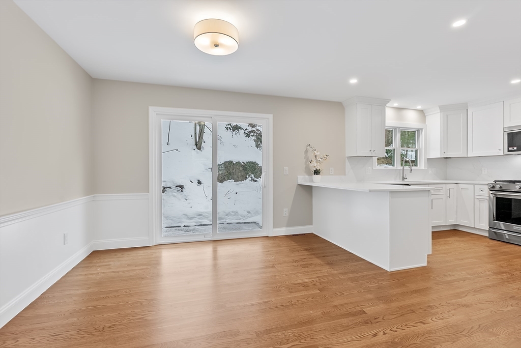 34 Pleasant Street, Unit 5 Wellesley, MA 02482 - Photo 6 of 31 a large white kitchen with kitchen island a sink wooden floor and a refrigerator